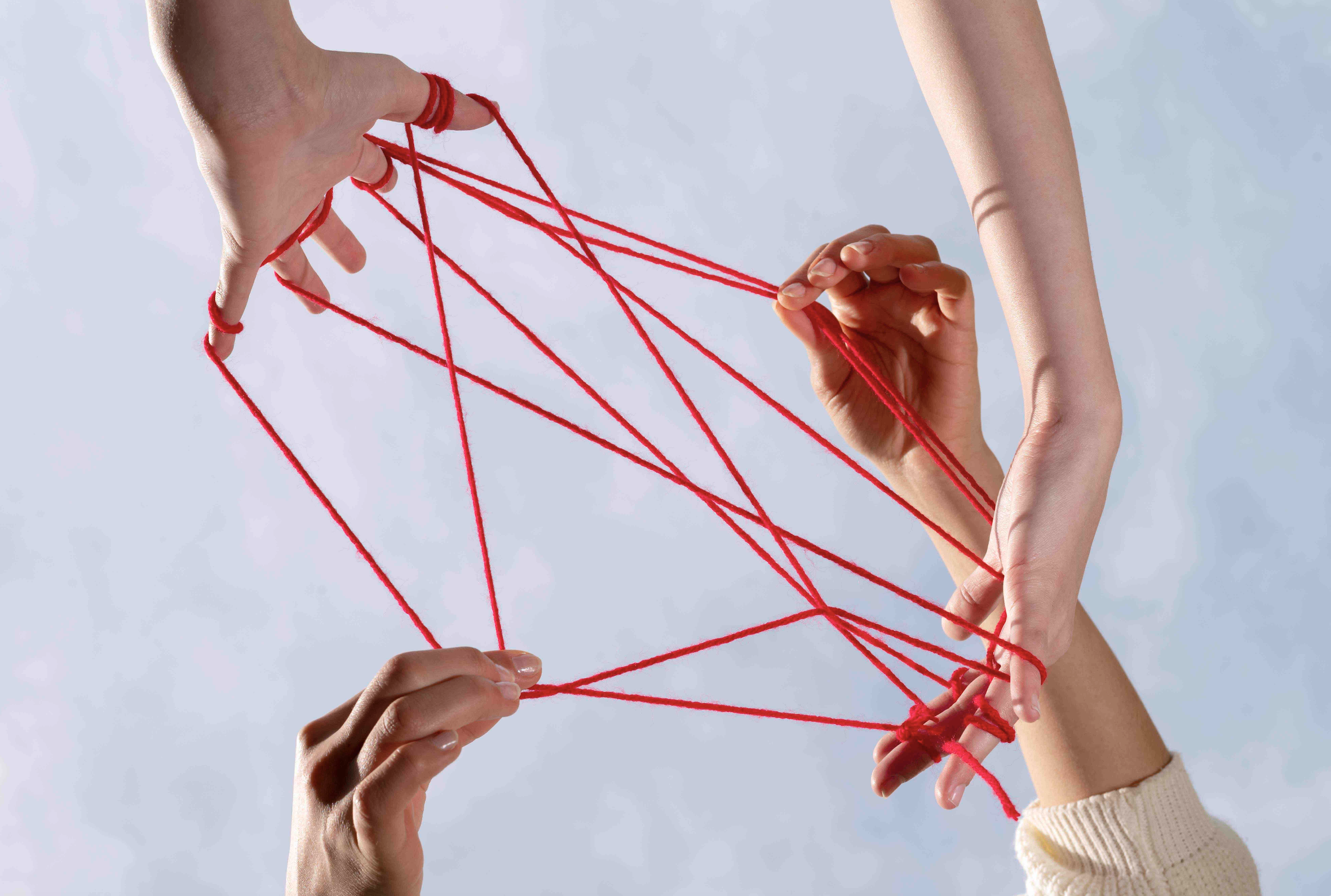Hände verknüpft durch rote Fäden symbolisieren die Kraft von Gemeinschaft und Beziehungen